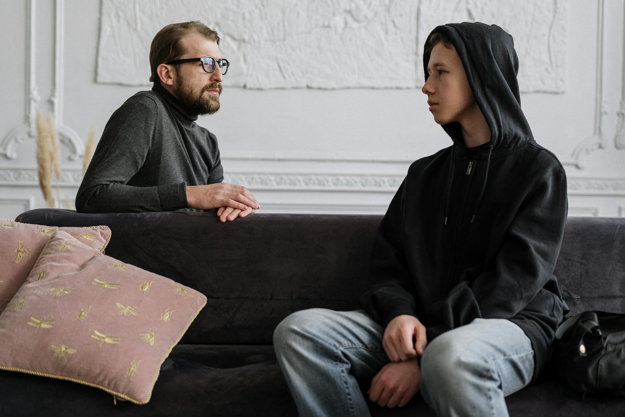 A psychologist and teenager engage in a counseling session in a cozy office setting.